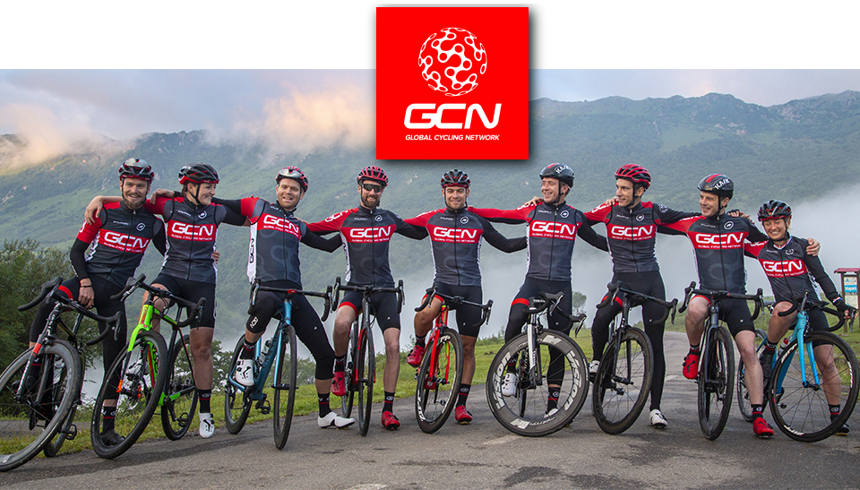 GCN's team pose with their bikes in front of a mountain scene